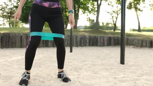 Woman Squats with Resistance Band at Park