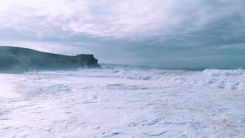 Expansive Coastal View with Rolling Waves and Overcast Skies