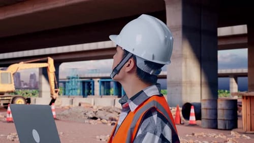 Nahaufnahme eines asiatischen männlichen Ingenieurs, der auf einer Baustelle an einem Laptop arbeitet