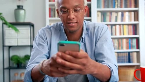Man with Glasses Using Mobile Phone Indoors
