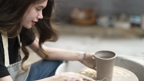 Young women is making earthenware at workshop.