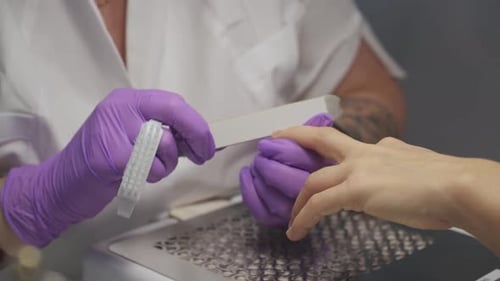 Beauty Technician Filing Fingernails in Salon