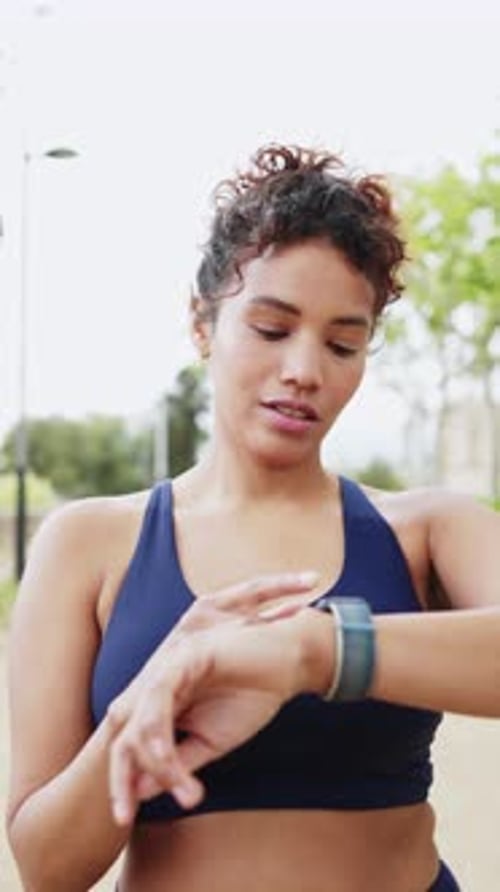 Woman Checking Fitness Tracker After Exercise in Park