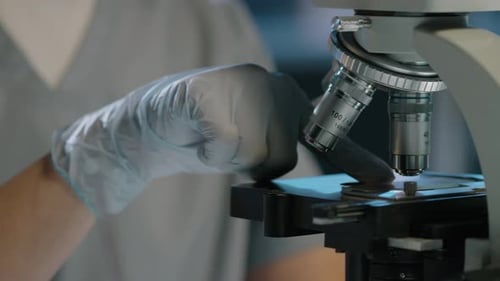 Hands of Anonymous Scientist Placing Specimen Slide under Microscope