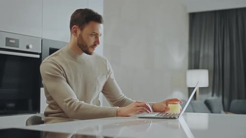 Man Working on Laptop in Modern Kitchen