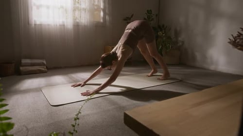 Girl Performing Downward Facing Dog Asana on Yoga Mat Alone at Home