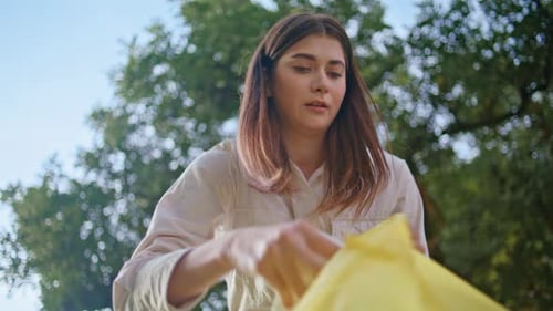 Mujer ecológica limpia la contaminación en el parque con una bolsa de plástico: primer plano de una voluntaria