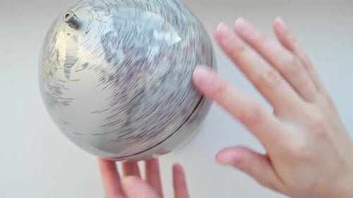 Die Hand dreht einen grauen Globus und wählt einen zufälligen Punkt auf der Karte aus, der den Globus darstellt