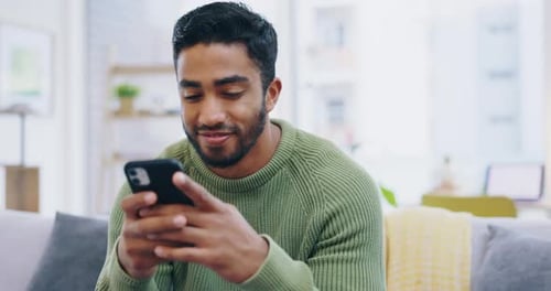 Man Uses Phone on Couch at Home
