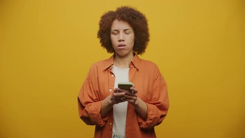 Woman Looks Anxious at Phone With Hand on Forehead