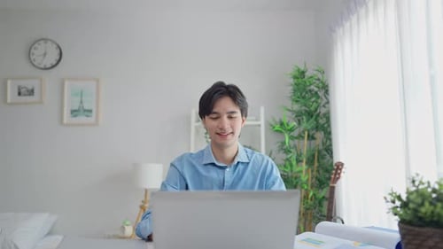Young Man Opens Laptop and Begins Working at Desk