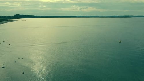 aerial shot low waves in a calm sea before sunset, near coast and other shore