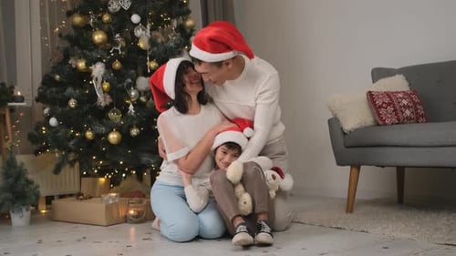 Loving Family Hugging by Christmas Tree Indoors