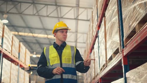 Man worker checks products stock inventory in the retail warehouse full of shelves