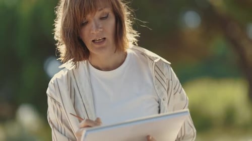 A Woman Sitting in the Park Painting with Watercolors and Talking