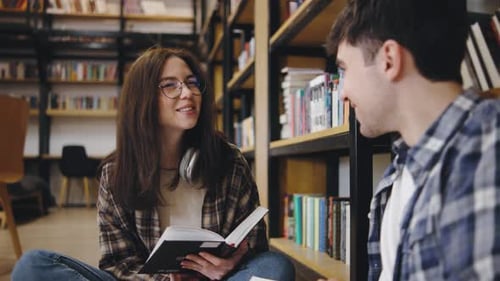 Young People Share a Moment in a Library While Reading a Book and Enjoying Each Other's Company in