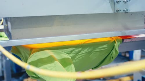 Freshly Screen Printed Shirt Curing Under Heat Lamp at Busy Print Shop Production Line