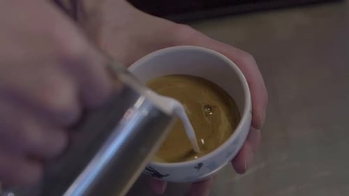 Slow Motion Of A Barista Pouring Steamed Milk Over Coffee. Making Latte Art In A Cup, close up