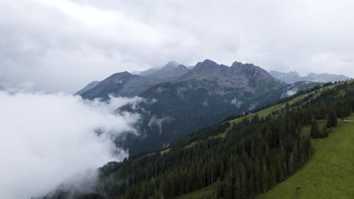 Scenic aerial view of a green slope of high mountain in a natural landscape with low cloud cover