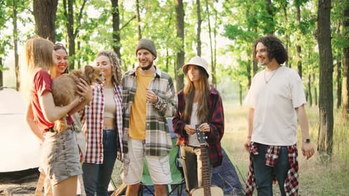 A Group of Cheerful Friends Tourists are Relaxing in a Green Forest with Tents an Acoustic Guitar