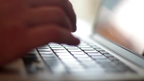Man typing on a laptop in home studio with shallow depth of field