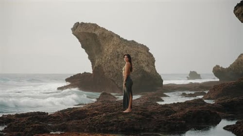 Woman Standing on Rocky Beach at Low Tide