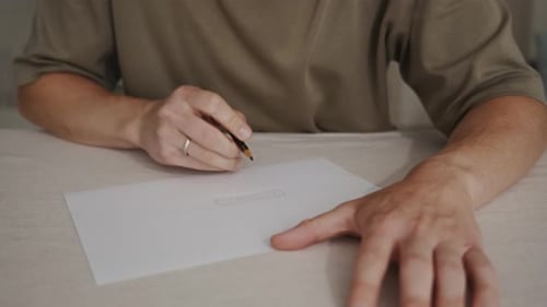 Man Drawing on Paper with a Pencil Indoors