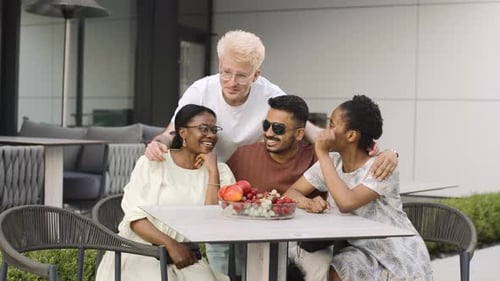 Multiethnic friends are gathered around a table at an outdoor cafe