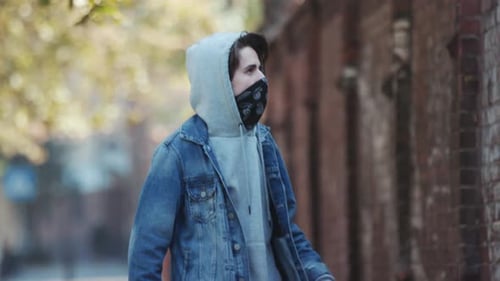 Jovem anônimo em balaclava de pé ao lado da parede e segura tinta spray Act of Vandalism Street