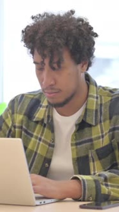 Young Man Working on Laptop at Desk Indoors