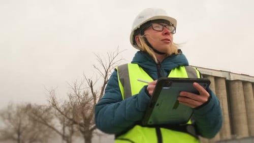 Young woman contractor construction in helmet and vest with tablet for engineering and management