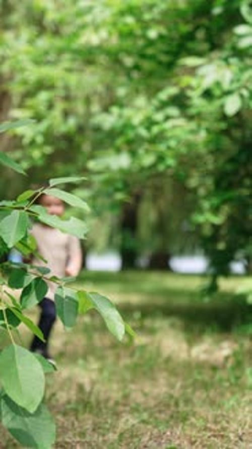 Cute happy Caucasian baby boy running joyfully in the park in summer.