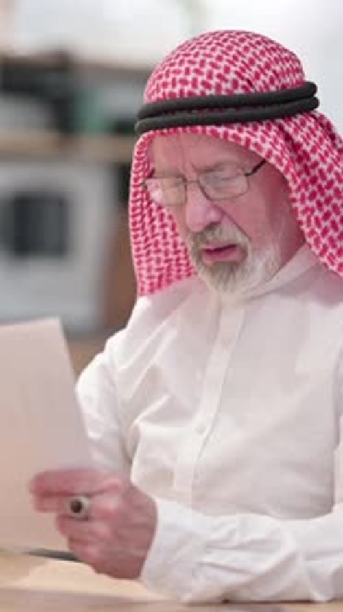 Senior Man in Traditional Dress Reads Document