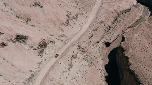 Orangefarbener Geländewagen fährt auf der Canyonstraße neben der Schlucht, Luftaufnahme