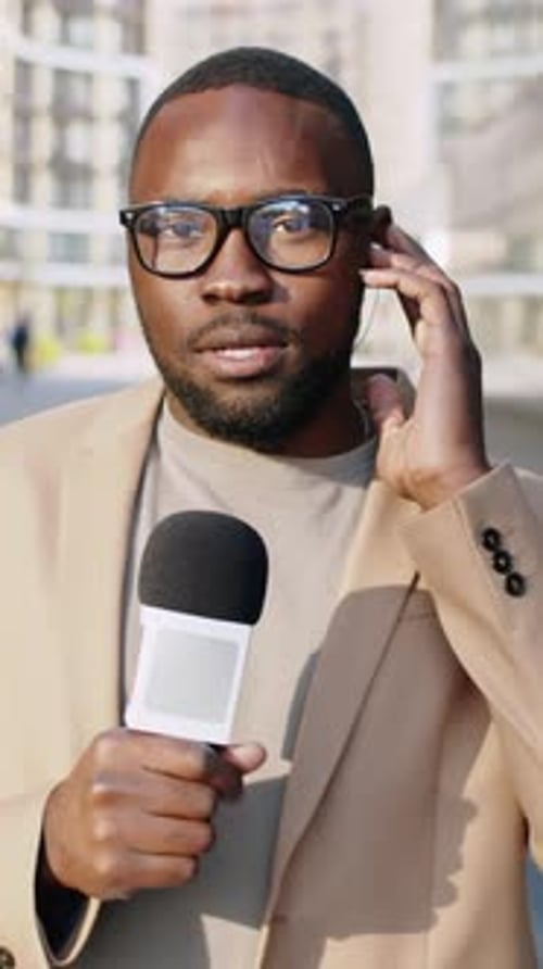 Man Reporting News Holding Microphone Wearing Suit and Glasses