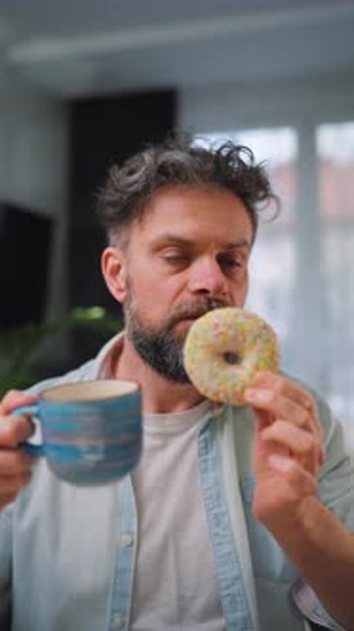 Sweet Addiction Concept A Man Eats a Donut and Drinks Coffee Vertical