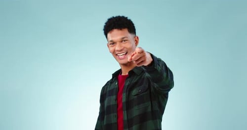 Gesicht, Lächeln und Mann, der auf dich zeigt, um im Studio zu wählen, zu entscheiden und auszuwählen, isoliert auf blauem Grund