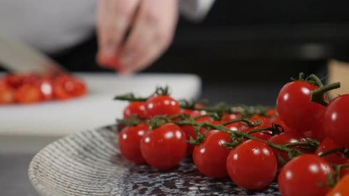Male Hands Holding Knife Cutting Cherry Tomatoes for Salad or Dish