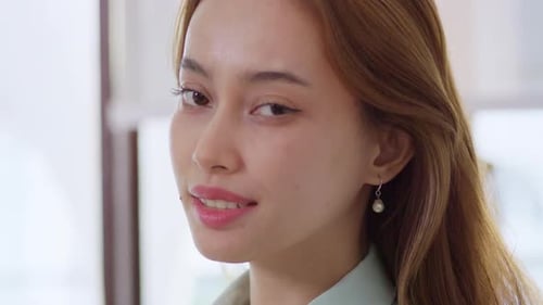 A confident young professional woman smiles warmly in an office embodying positivity and success.