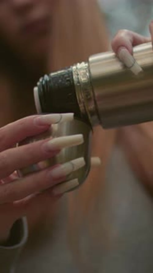 CloseUp of Woman Pouring Water From Thermos Cap in Serene Forest