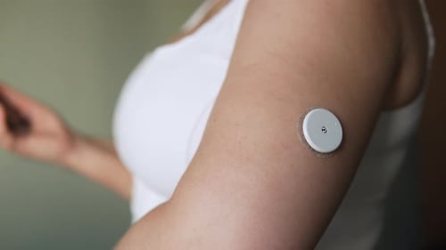 Woman scanning glucose monitor with mobile phone