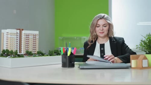 Business Mogul Smiling While Closing Book at Office Desk