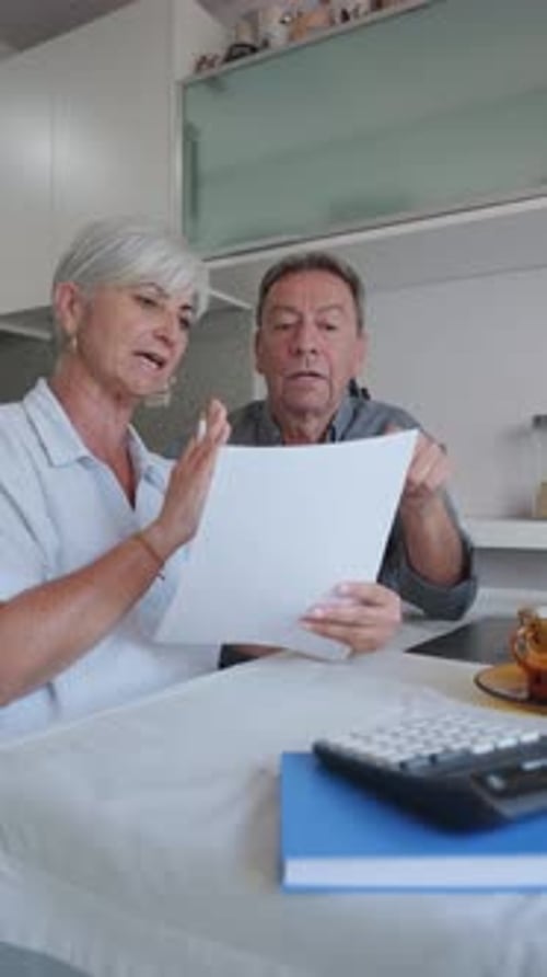 Mature Couple Discussing Paperwork at Kitchen Table
