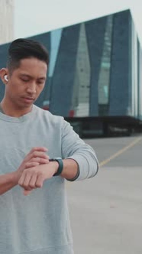 Man Checks Smartwatch While Jogging in the City