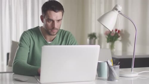 Focused Man Works from Home on Laptop