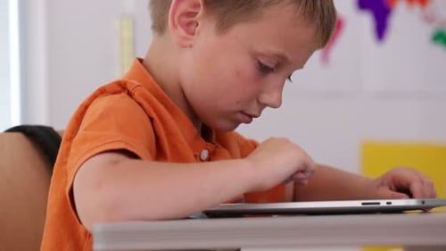 Un alegre colegial usa una tableta digital para un primer plano de la educación primaria