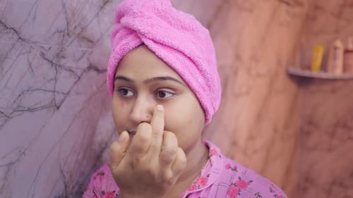 young indian women applying under eye cream in the bathroom.