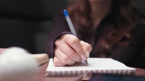 Close Up Of Female Hand Writing In Notebook With Acrylic Nails