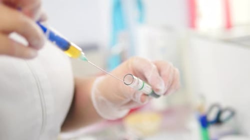 Close Up Lab Tech Draws Liquid into Vial