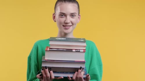 Smiling Happy Student Girl with Stack of Books From Library on Yellow Background
